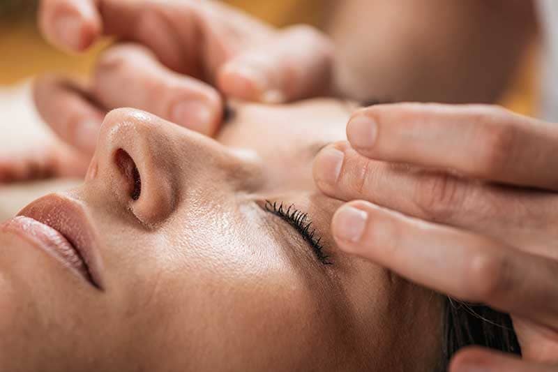 Woman getting a facial acupressure massage treatment.