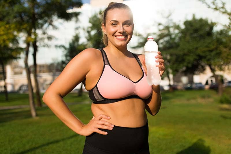 Woman exercising in the park and holding a water bottle.