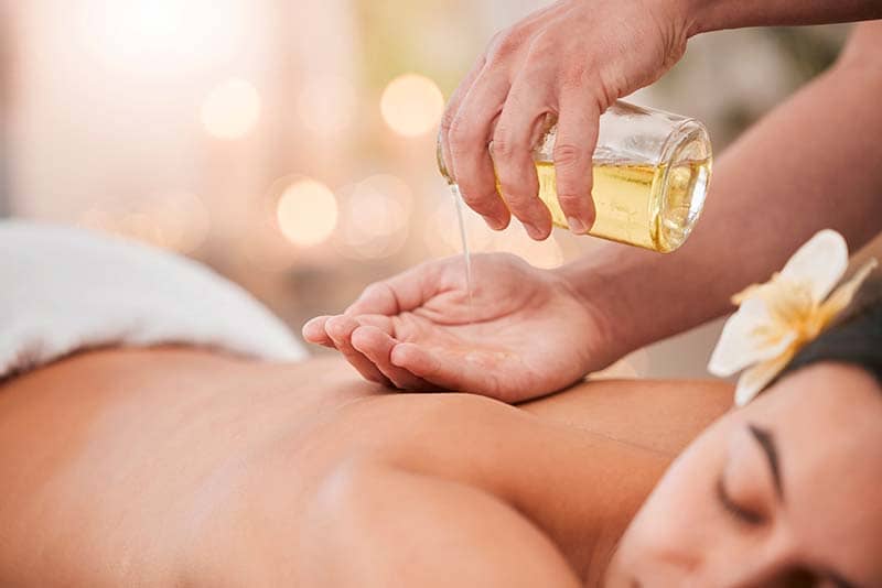 Masseuse pouring ayurvedic massage oil in their hand.